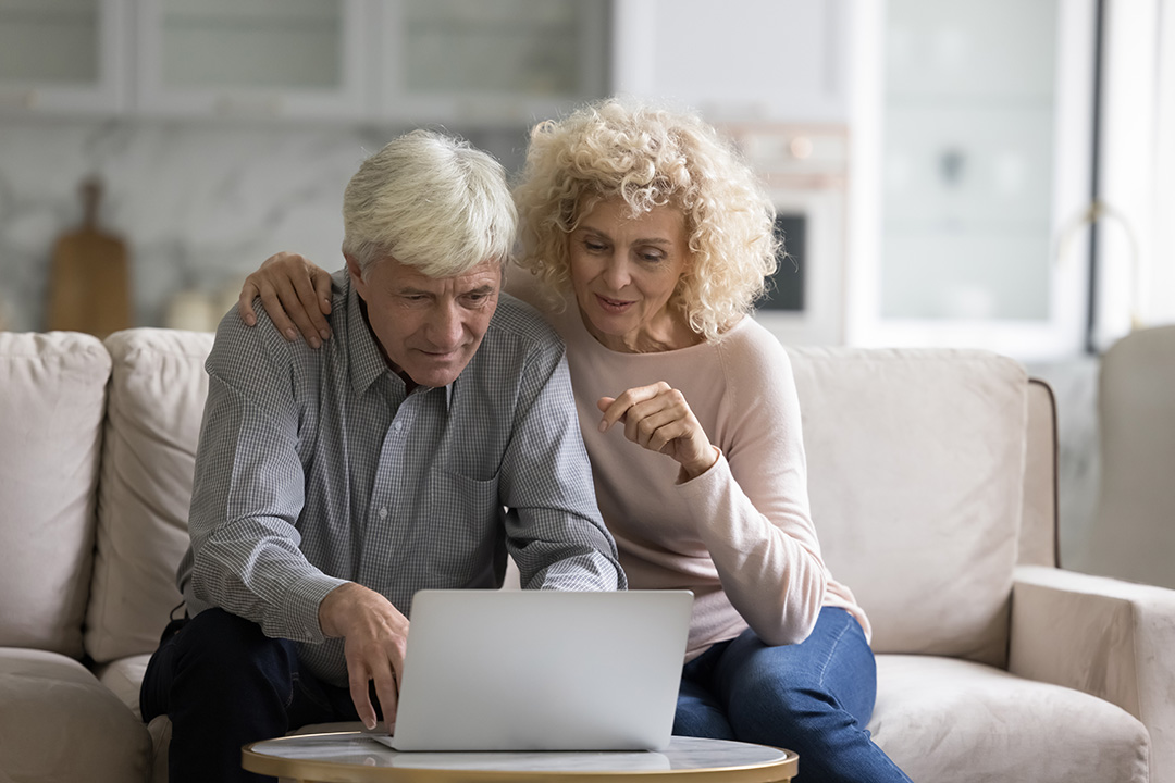 Couple sitting on couch staring at laptop deciding on options for their Bullfrog Spas A-Series Hot Tub