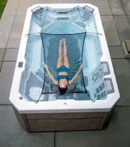 Swim Spas are not just for laps - Woman floating in a hammock in her Bullfrog Spas Swim Spa - Maine