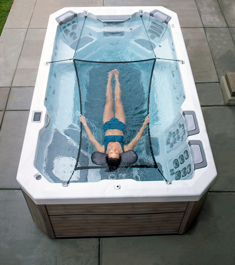 Swim Spas are not just for laps - Woman floating in a hammock in her Bullfrog Spas Swim Spa - Maine